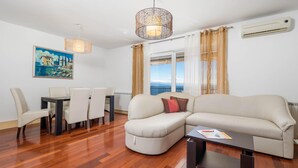 A modern living room with a sofa, dining table, chairs, and a painting on the wall. - Beautiful Home in Icici With Wifi and 3 Bedrooms (Opatija)