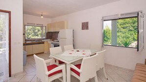 Une cuisine compacte comprenant un coin repas, un réfrigérateur, une cuisinière et une fenêtre donnant sur un espace verdoyant.