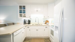 Een moderne keuken met witte kasten, een ingebouwde vaatwasser, een spoelbak en een koelkast.