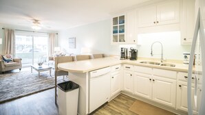 Een moderne keuken met witte kasten, een vaatwasser, een koffiezetapparaat en een spoelbak.