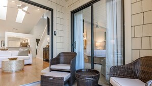 Un amplio salón con un sofá blanco, sillas de mimbre y una mesa de centro redonda.