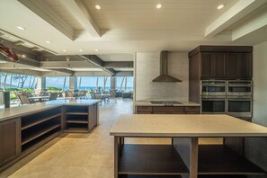 A modern kitchen with a large island, built-in ovens, and a view of the ocean.
