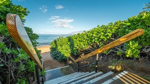 Eine Treppe führt zu einem Strand, gesäumt von üppiger Vegetation.