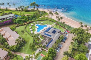 Vista aérea de un resort con piscina, playa y palmeras.