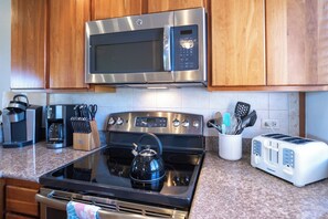 Una cocina con electrodomésticos de acero inoxidable, armarios de madera y encimeras de granito.