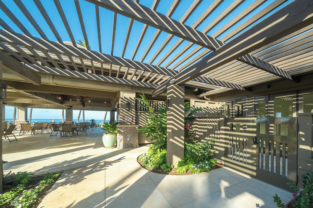 Eine Terrasse im Freien mit einer Pergola, Sitzgelegenheiten und Kübelpflanzen.