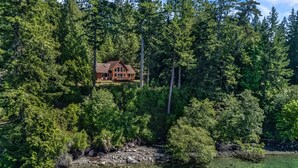 A cabin surrounded by dense forest and a clear lake. - Waterfront w/ Seasonal Dock! (Rendezvous Retreat) (Friday Harbor)