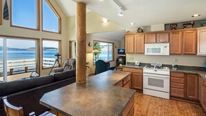 A modern kitchen with a large island, wooden cabinets, and a view of the ocean. - Waterfront w/ Seasonal Dock! (Rendezvous Retreat) (Friday Harbor)