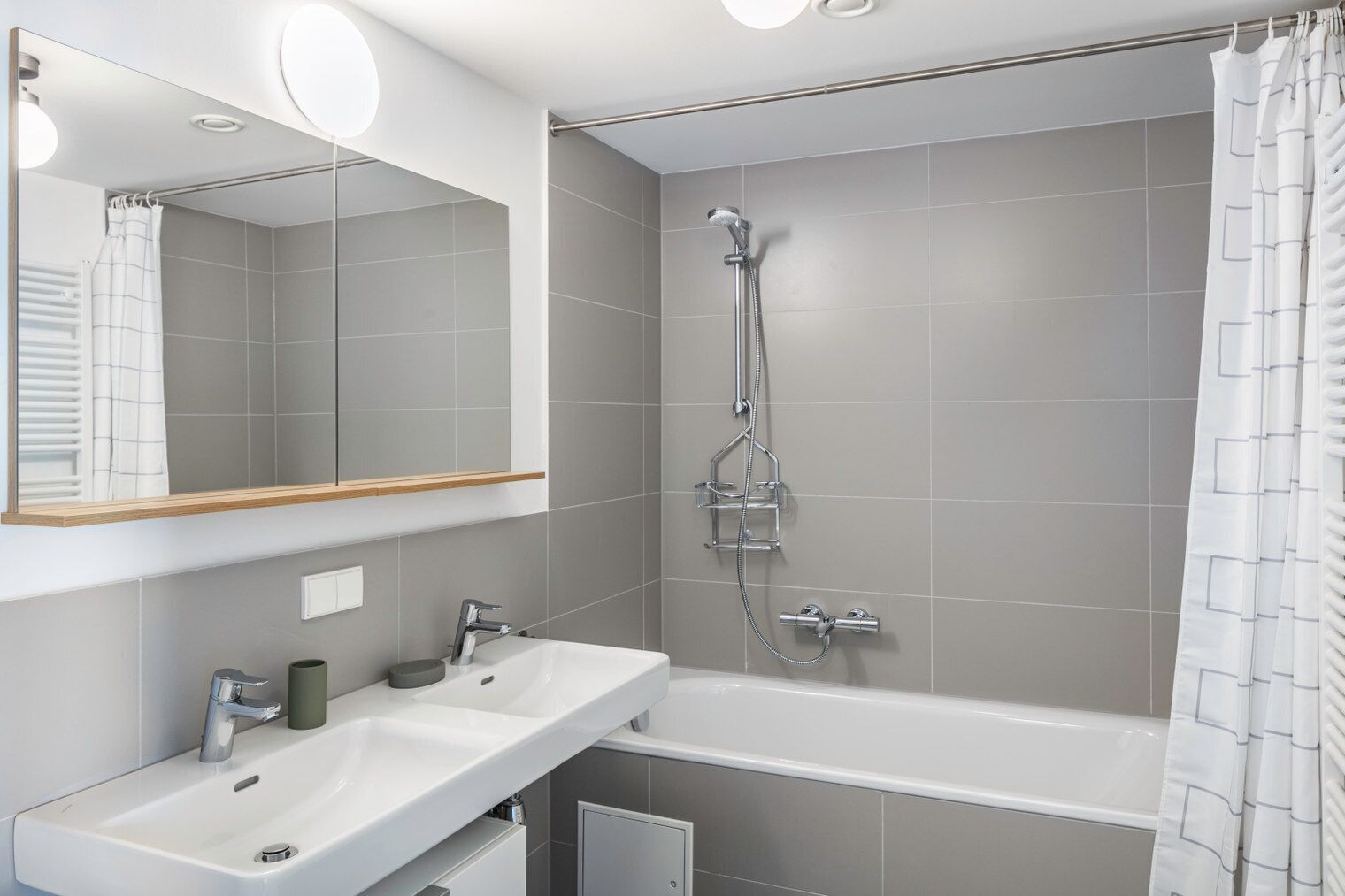 A modern bathroom with a large mirror, a bathtub, and a shower.