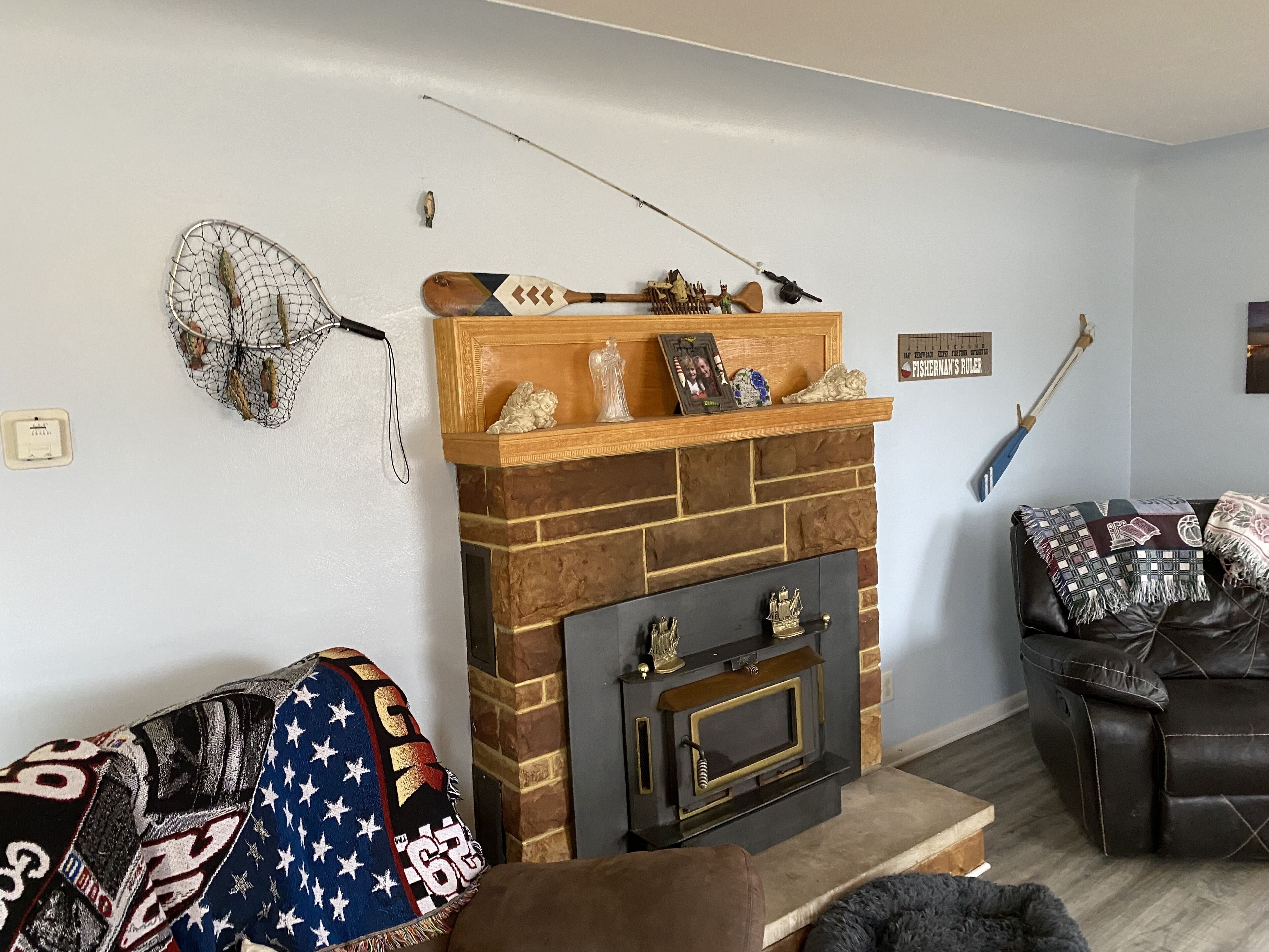 Un salon avec une cheminée en briques, une canne à pêche et un canapé en cuir.