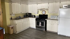 A kitchen with white cabinets, a stainless steel stove, a microwave, and a refrigerator. - Romantic House on the Lake-Hot Tub Pet Friendly-kayaks-Fishing Boat. Sleeps 8 (Pleasant Lake)