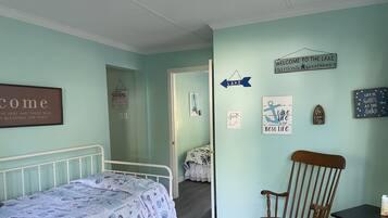A bedroom with a bed, a rocking chair, and a wall with various signs and decorations.