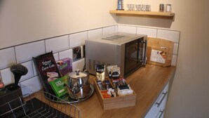 A kitchen with a coffee machine, a kettle, a box of tea bags, and a shelf with spices. - 1 Bed Flat - Sleeps 2 - Wifi (Pitlochry)