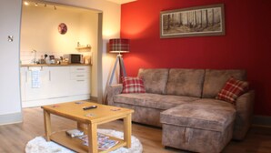 A living room with a sofa, a coffee table, a lamp, and a painting on the wall. - 1 Bed Flat - Sleeps 2 - Wifi (Pitlochry)