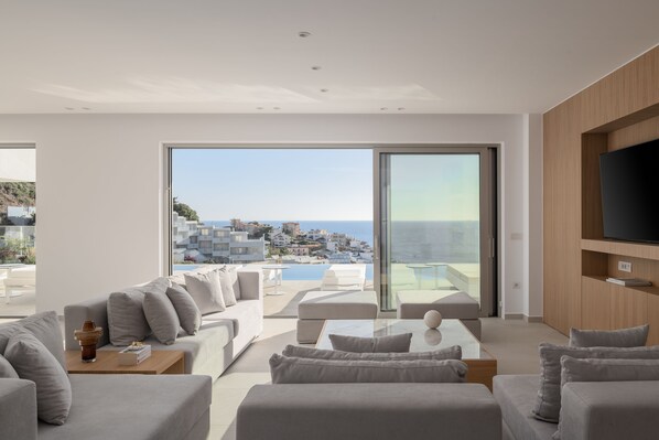 A modern living room with a large sliding glass door leading to a balcony with a city view.