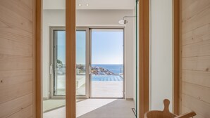 A modern interior with wooden paneling, a glass door leading to a balcony with a pool and ocean view. - Ode Iconic Residence, forever in blue - Best Villa (Bali)