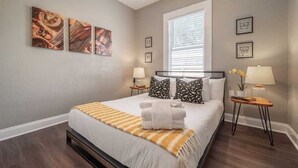 Habitación de hotel ordenada con una cama grande, dos mesitas de noche con lámparas y decoración en la pared.