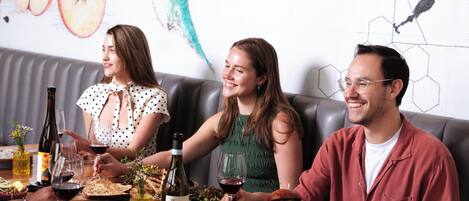 Un comedor con una mesa dispuesta para una comida, un sofá y una pared decorada con un mural floral.