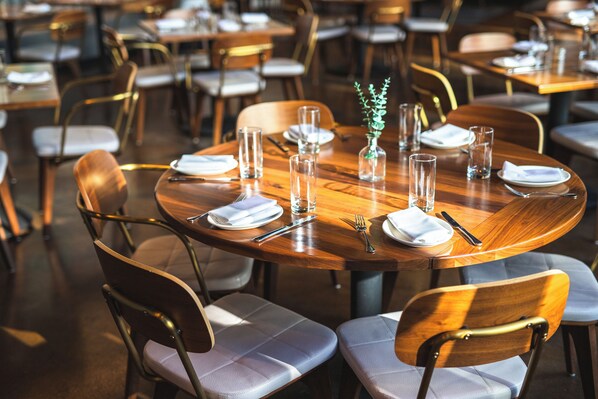 Un comedor con mesas redondas, sillas y vajilla dispuesta con cuidado.