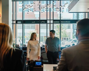 A modern interior with large windows, hanging pendant lights, and a visible street view outside. - Hyatt Centric Downtown Denver (Denver)