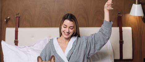 Una persona sentada en una cama con un perro, sosteniendo un vaso.