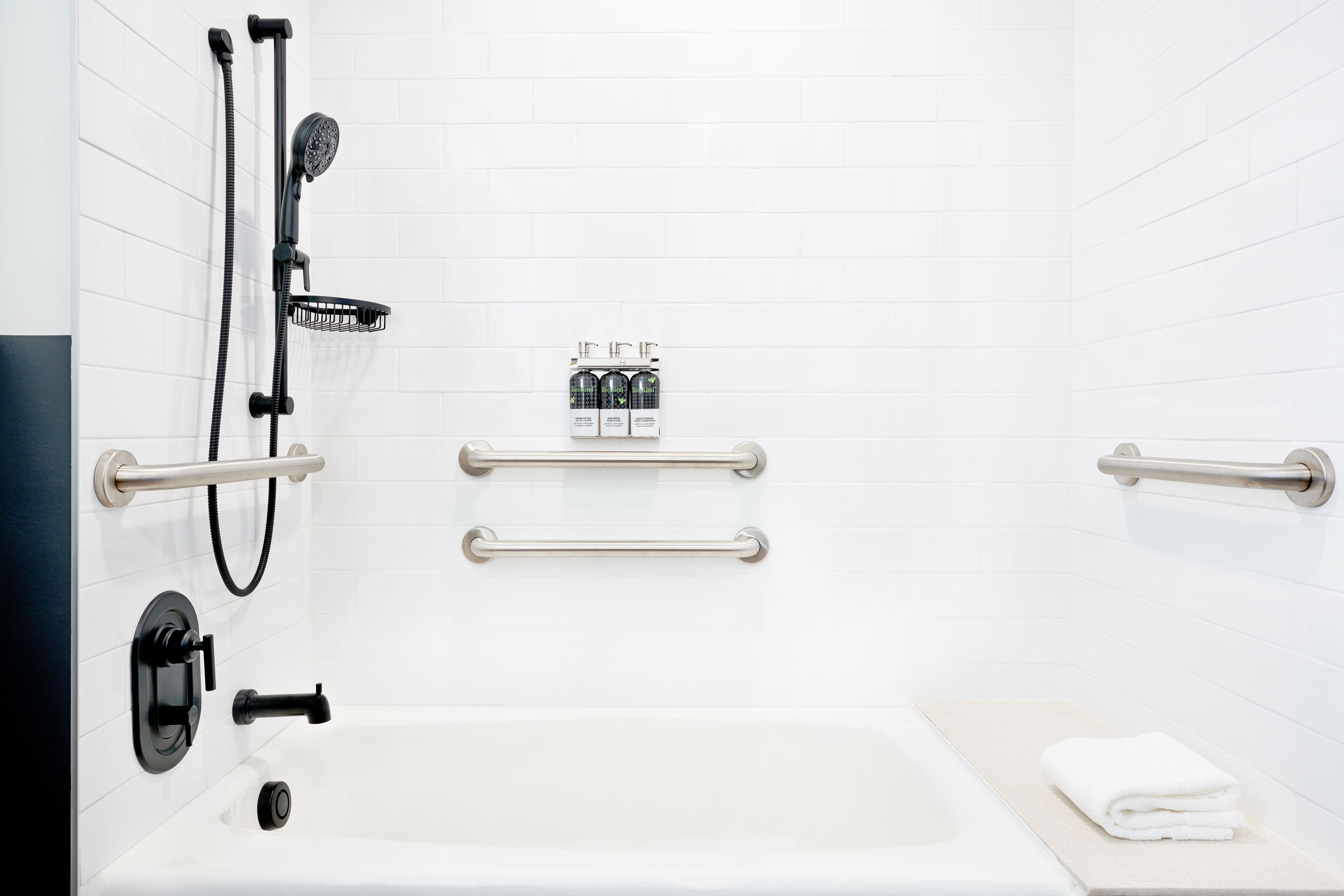 A modern bathroom with a bathtub, a shower with a handheld showerhead, and grab bars.