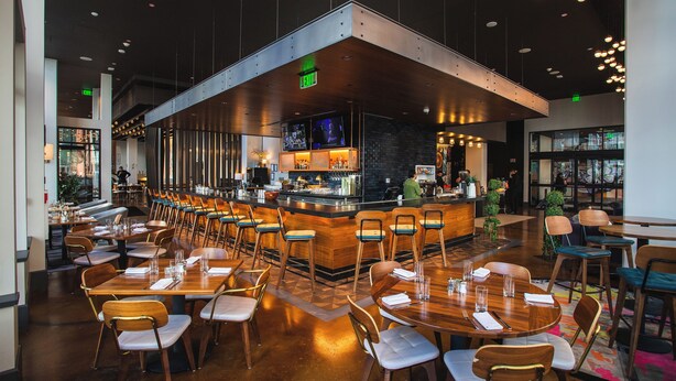 A modern restaurant with a central bar area, multiple seating options, and a contemporary interior design. - Hyatt Centric Downtown Denver (Denver)