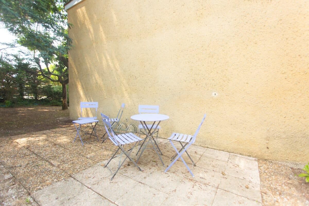 An outdoor patio with a yellow wall, a small round table, and four chairs.
