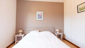 Een hotelkamer met een groot bed, twee nachtkastjes met lampen, een ingelijst schilderij aan de muur en een betegelde vloer.