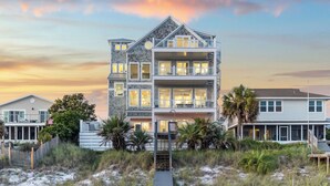 A multi-story beachfront property with a balcony, a covered porch, and a staircase leading to the entrance. - Luxe group-friendly beachfront escape with pool, hot tub, & expansive Gulf views (West Panama City Beach)
