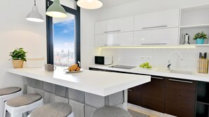 A modern kitchen with a central island, white cabinetry, and a view of the city through a large window. - Modern Villa Barcolana with a swimming pool (Baderna)