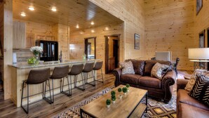A wooden cabin interior with a kitchen, dining area, and living room. - 🏊 OUTDOOR & 👙 INDOOR PRIVATE POOL CABIN | 🎮 Game Room 🕹️ (Sevierville)