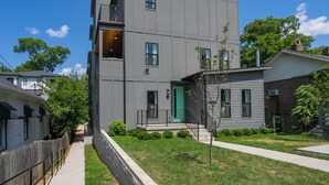 Un edificio moderno de varios pisos con fachada gris, una puerta verde y un pequeño balcón.