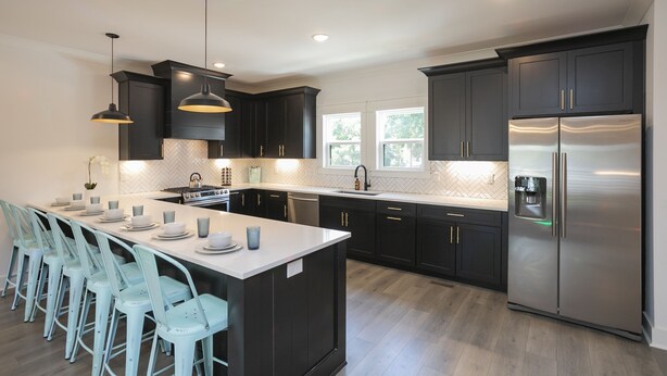 Una cocina moderna con una isla central, armarios negros, electrodomésticos de acero inoxidable y sillas azul claro.
