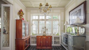 A room with a wooden cabinet, a radiator, a chair, and a table with a lamp.