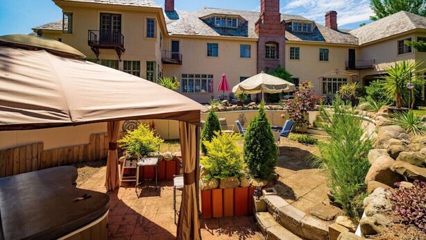 A spacious outdoor patio with a covered seating area, a swimming pool, and a well-maintained garden.