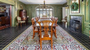 A formal dining room with a large table, ornate chairs, a chandelier, and a fireplace.
