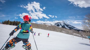 A person skiing on a snowy slope with a mountain in the background.
