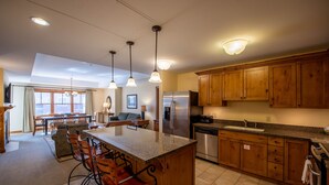 A spacious kitchen with wooden cabinets, a stainless steel refrigerator, and a granite countertop. - Spacious 3 Bedroom Condo with Balcony in Mountaineer Square 3 Condo - No Cleaning Fee! by RedAwning (Crested Butte)