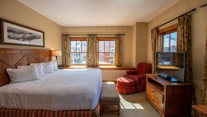 A hotel room with a large bed, a TV on a wooden cabinet, a window with curtains, and a red chair. - Spacious 3 Bedroom Condo with Balcony in Mountaineer Square 3 Condo - No Cleaning Fee! by RedAwning (Crested Butte)