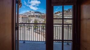 Ein Balkon mit Metallgeländer, Blick auf einen verschneiten Berg und Gebäude im Hintergrund.