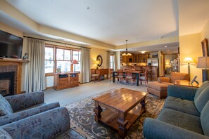 A spacious living room with a fireplace, a dining area, and a kitchen. - Two Bedroom Condo with Balcony over Mountaineer Square - Just Steps from the Slopes! 2 Condo - No Cleaning Fee! by RedAwning (Crested Butte)