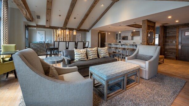 A spacious living area with a high ceiling and exposed wooden beams, a sofa set, a coffee table, and a dining area with chairs and a table. - Three Bedroom Mountain Chic 6th Floor Penthouse with Amazing View 3 Condo - No Cleaning Fee! by RedAwning (Crested Butte)