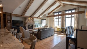 A spacious living area with a stone fireplace, wooden beams, a marble bar, and comfortable seating. - Three Bedroom Mountain Chic 6th Floor Penthouse with Amazing View 3 Condo - No Cleaning Fee! by RedAwning (Crested Butte)