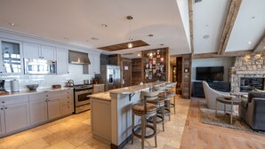 A spacious kitchen with modern appliances, a large island with bar stools, and a stone fireplace. - Three Bedroom Mountain Chic 6th Floor Penthouse with Amazing View 3 Condo - No Cleaning Fee! by RedAwning (Crested Butte)