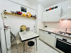 A compact kitchen with white cabinets, a marble countertop, and a gas stove.