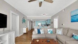 A spacious living room with a large sofa, a wooden coffee table, and a ceiling fan.