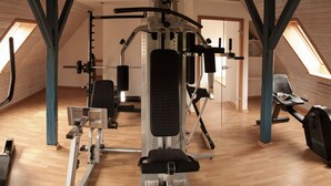 A gym with a ceiling fan, exercise equipment, and a treadmill. - Das Altenteil (Stoltebuell)