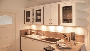 A modern kitchen with white cabinetry, a double sink, and a built-in oven. - Das Altenteil (Stoltebuell)