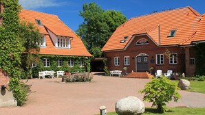A courtyard with brick buildings, outdoor seating, and a small garden. - Das Backhaus 2 (Stoltebuell)